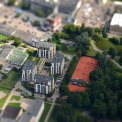 Ēku komplekss un sarkani tenisa korti Rīgā no putna lidojuma ar miniatūras efektu.
